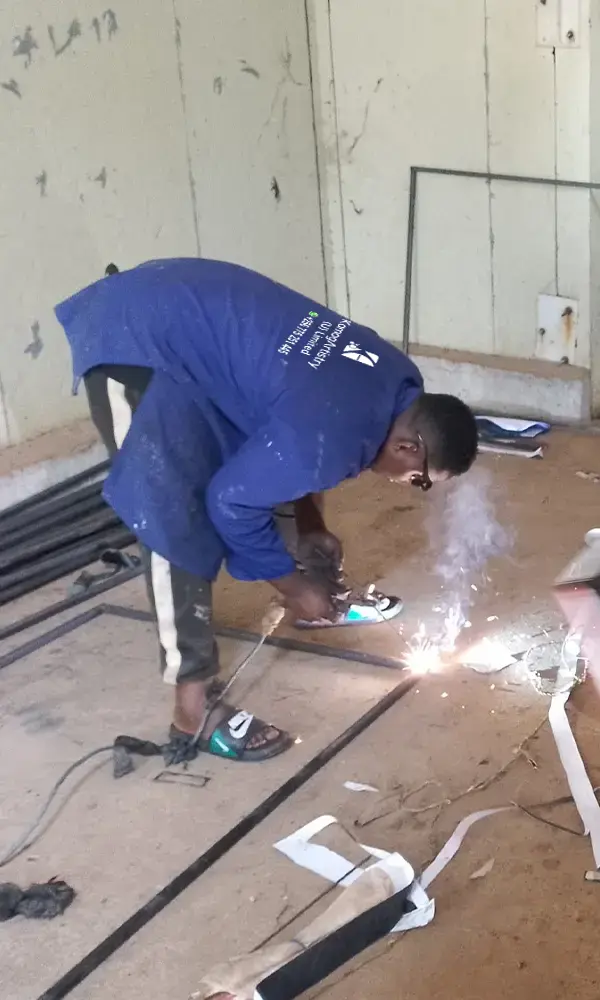 Welding in progress on a Goodwill hardware signage frame in Kampala