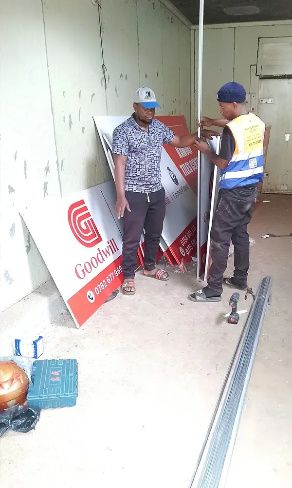 Aluminium edging being measured and fitted to Goodwill framed PVC signage