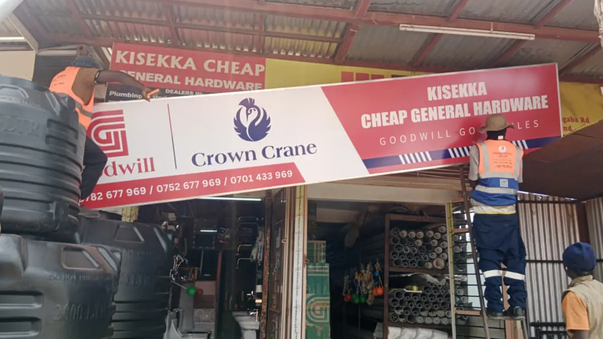 Five-metre storefront signage being secured at Kisekka Cheap General Hardware • Kansanga for the Goodwill and Crown Crane rollout