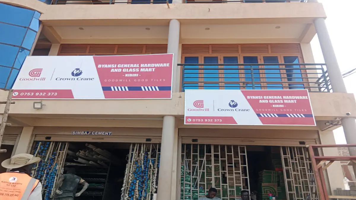 The paired frontage signs seen together at Byansi General Hardware • Kibiri for the Goodwill and Crown Crane rollout