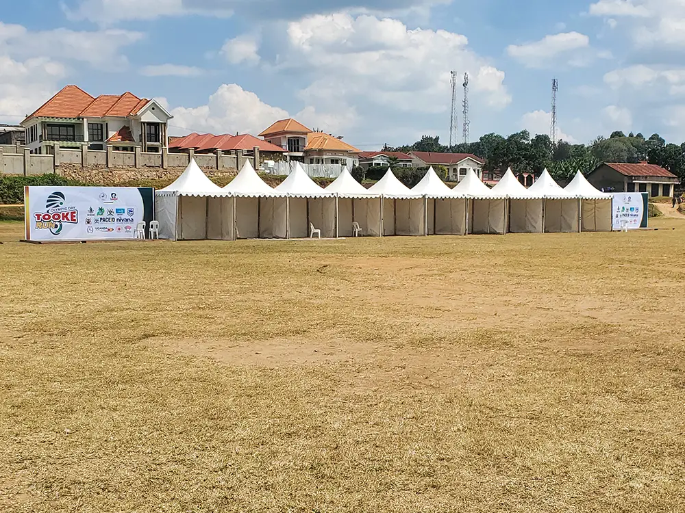Two sponsor backdrops beside mini tents — Distant view of the two installed outdoor photo backdrops beside the mini tent line at the field.